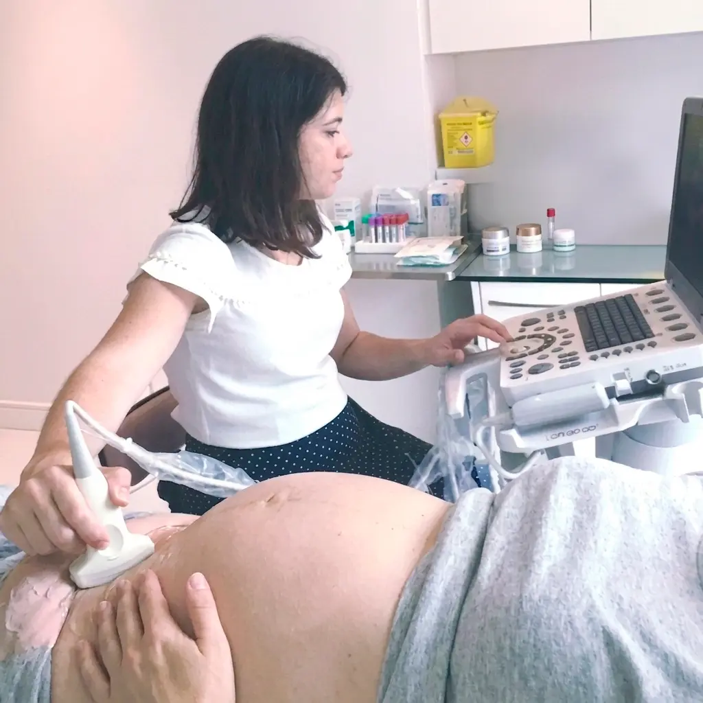 Dra. Mariana Romanowski realizando exame de ultrassom em gestante deitada em consultório