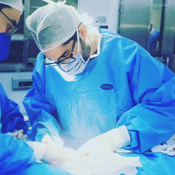 Dr. João Abelha com roupa cirúrgica fazendo cirurgia em centro cirúrgico.