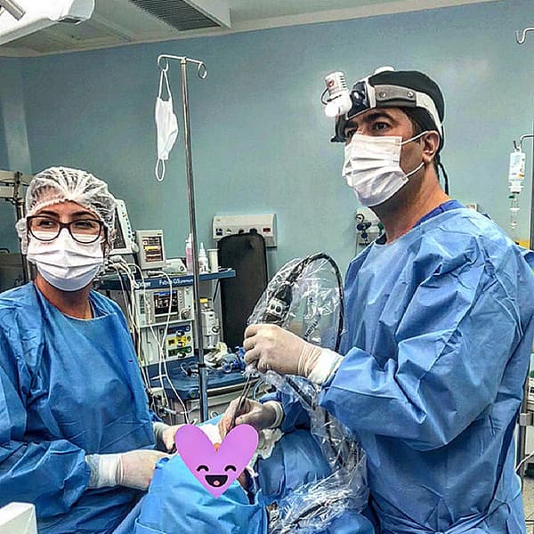 Dr. Mohamad e sua assistente, ambos em um centro cirurgico e aparentemente realizando uma cirurgia.