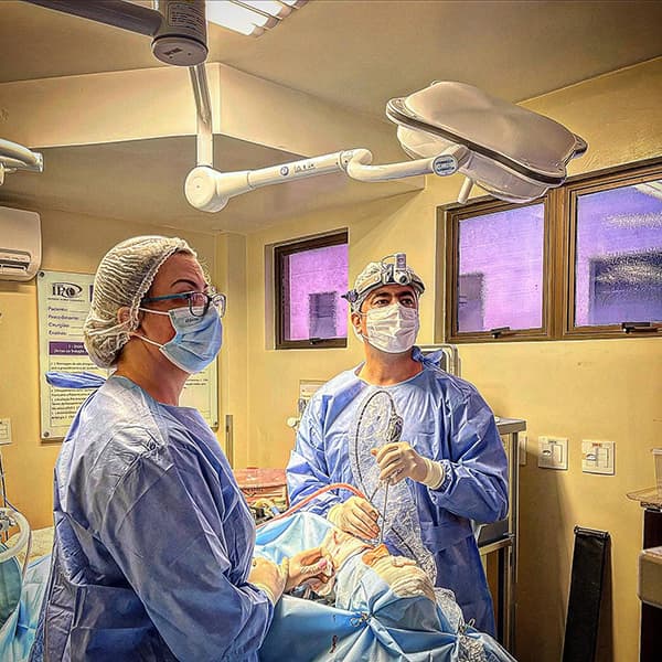 Dr. Mohamad e sua assistente, ambos em um centro cirurgico e aparentemente realizando uma cirurgia.