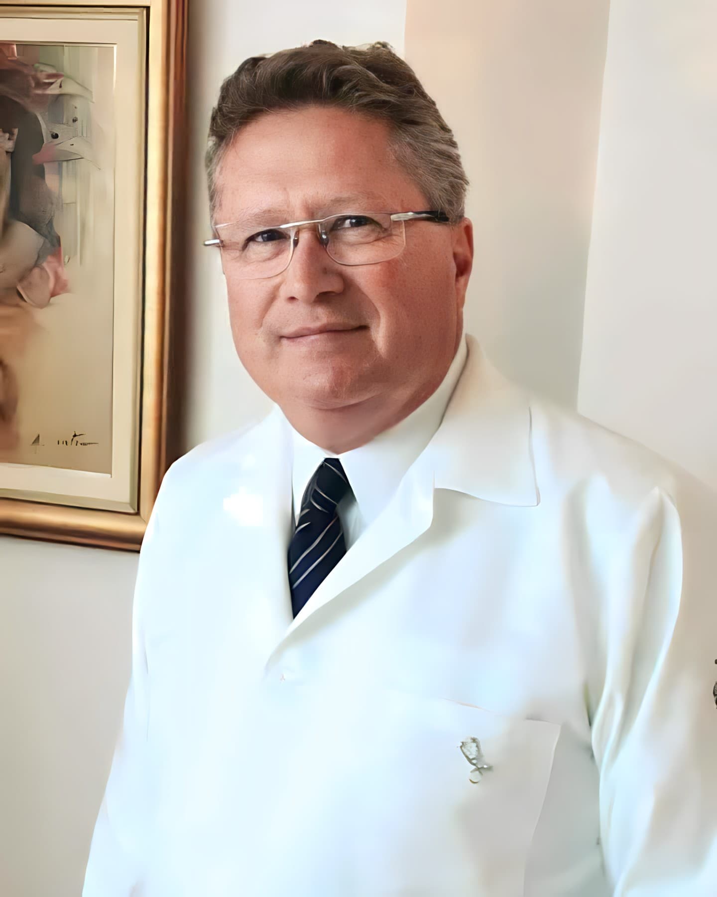 Dr. Carlos Rogério Temporal, obstetra e ginecologista em Curitiba, aparenta ter cerca de 50 anos, com cabelos curtos castanhos claros, sem barba. Ele está de pé em seu consultório, sorrindo levemente para a câmera. Usa uma camisa branca, gravata preta e jaleco branco, além de óculos que complementam seu visual profissional. Ao fundo, uma parede branca com um quadro discreto adiciona um toque de serenidade ao ambiente.