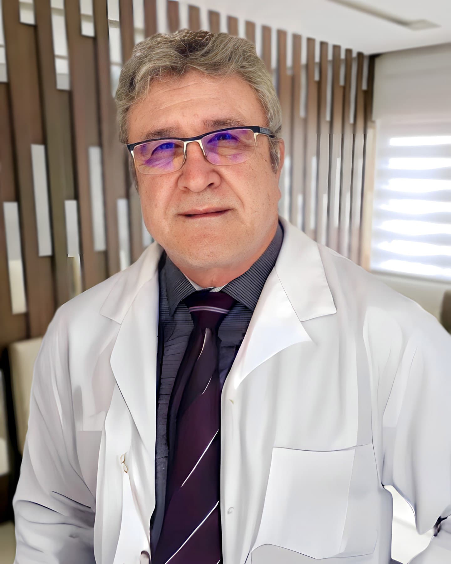 Dr. Francisco Xavier da Silva, otorrino em Curitiba, meia idade, cabelos curtos castanhos médios, levemente sorrindo e olhando para a câmera, ele está de pé e atrás uma parede de madeira e espelhos e cadeiras, ele está de óculos, vestindo uma camisa cinza, gravata e jaleco branco.